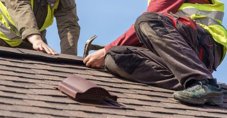 Roofers installing shingles on a residential roof in The Woodlands Texas.
